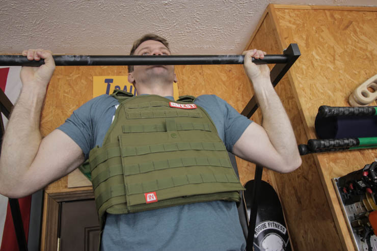 man performing a pullup with the army green Invest Pro Weight Vest