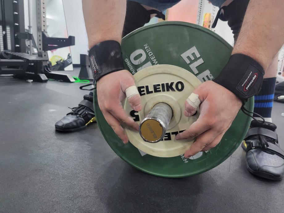 A man adjusts weights on the IWF Weightlifting Competition Bar