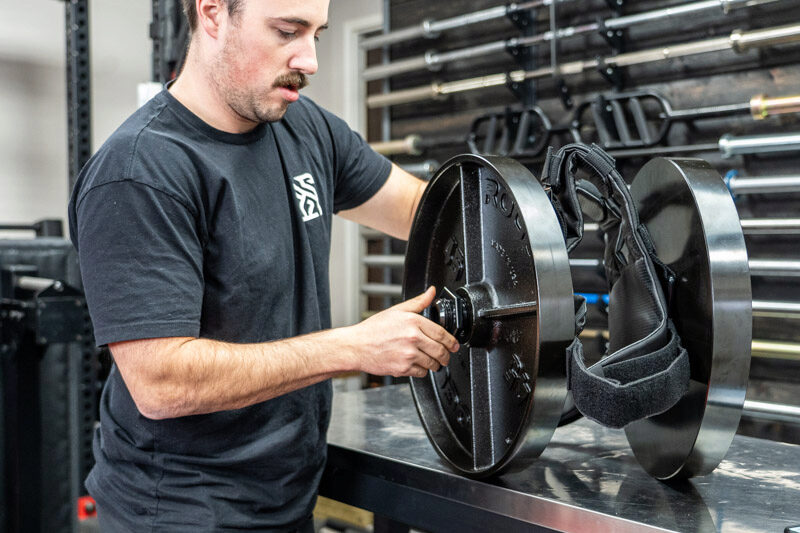 A man securing 45 lb. Rogue Fitness weight plates to the Kensui EZ-VEST Plate-Loadable Weight Vest.