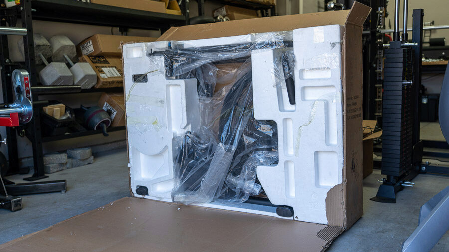 The box that held the fan bike has been opened and you can see Styrofoam, plastic wrap, and the bike pieces.