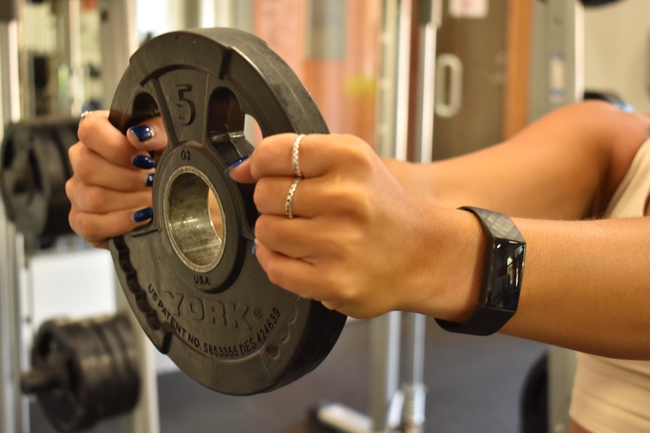 Person holding weight plate wearing Fitbit charge 4