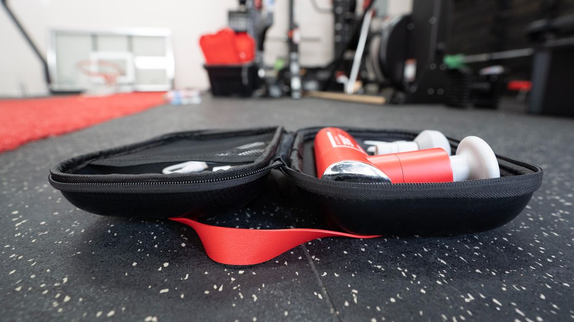 Side view of the REP Rapidstrike Massage Gun in its carrying case in a gym.