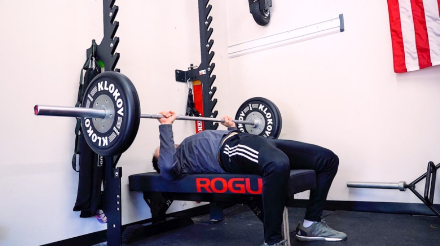 Man bench pressing weights in a home gym