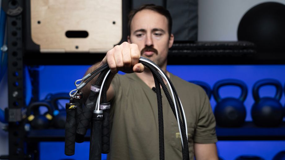 A man holding multiple jump ropes in one hand and looking at them in comparison.
