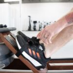 A close-up view of someone strapping their feet into the foot cradles of a rowing machine
