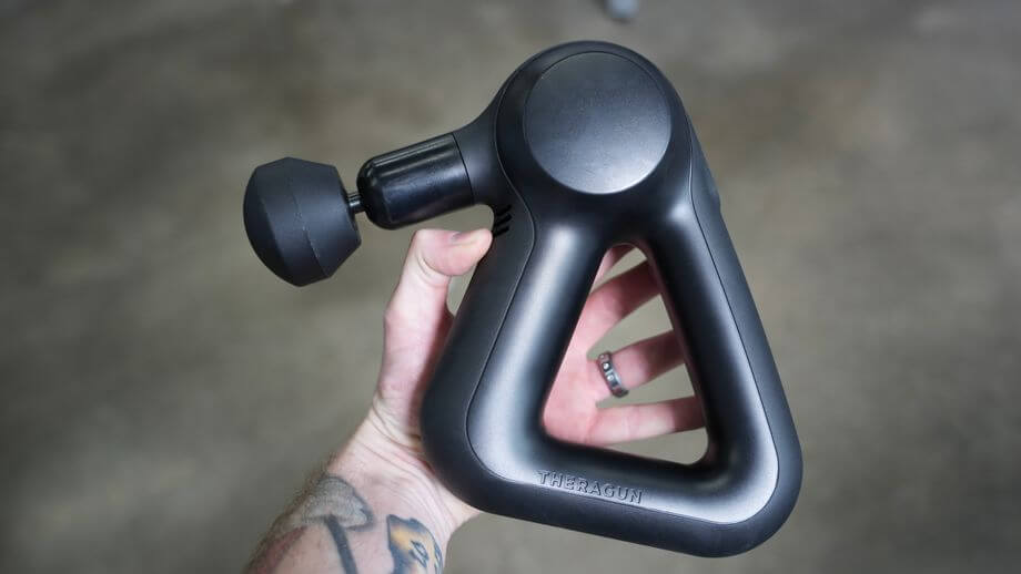 Holding the Theragun prime in hand.