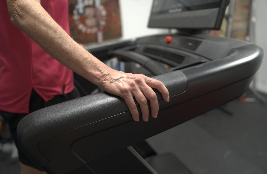 A senior using the handrails on a NordicTrack Commercial 2450 Treadmill