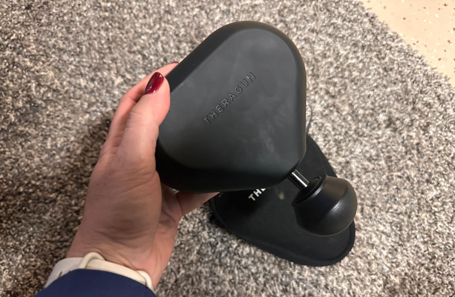 A person inspects one of the best mini massage guns.