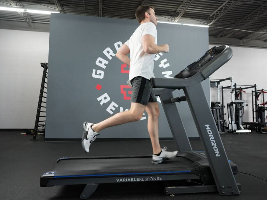 Person in shorts and a white t-shirt running on a Horizon 7.4 treadmill