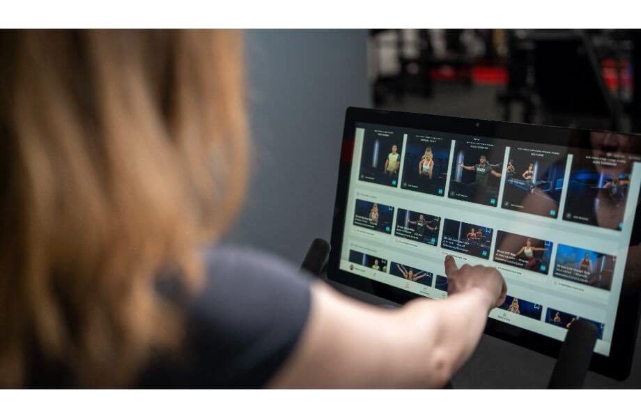 A woman using the touchscreen of the peloton bike