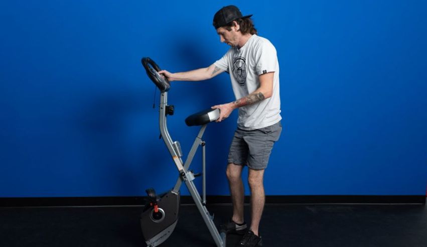 An image of a man folding the Exerpeutic folding magnetic exercise bike