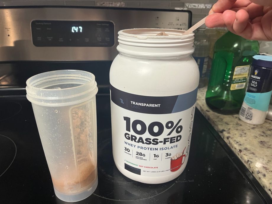 Person scooping from a container of Transparent Labs Whey Isolate