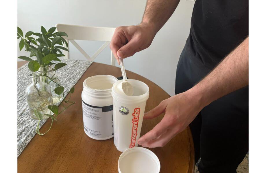 Image of person adding a scoop of Transparent Labs Bulk to a shaker cup