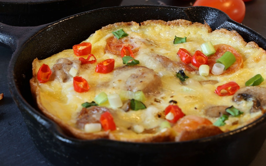 An image of a frittata baked with eggs and vegetables in a cast iron skillet