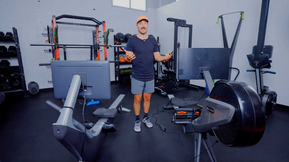 Coop standing between two rowing machines in a gym setting