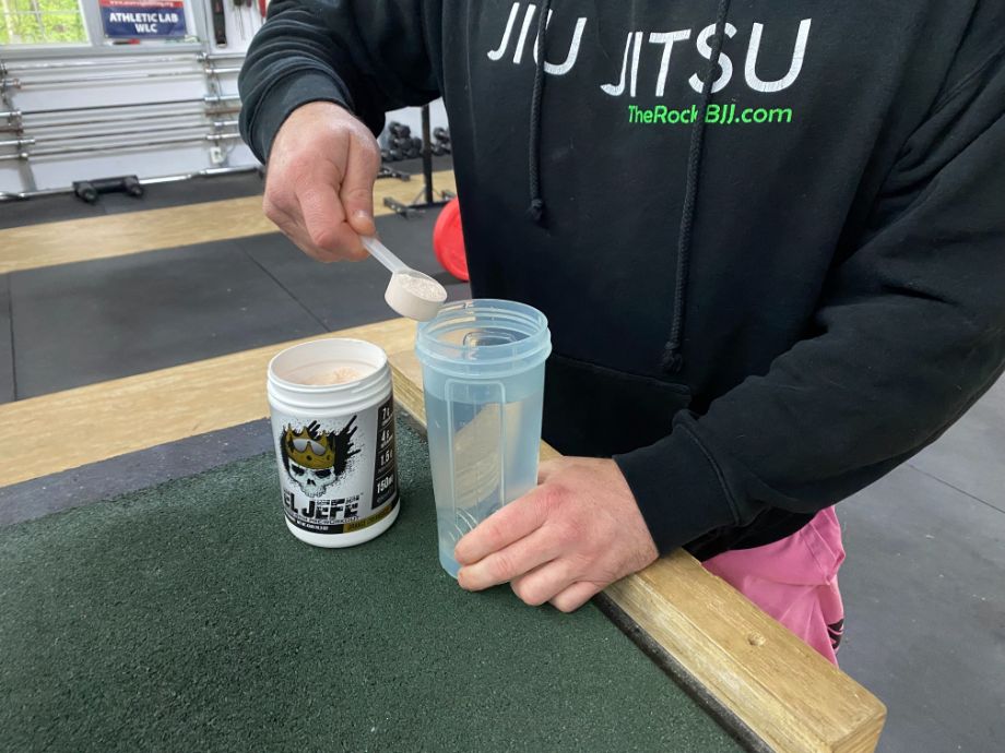 Scooping El Jefe Pre-Workout into a shaker cup