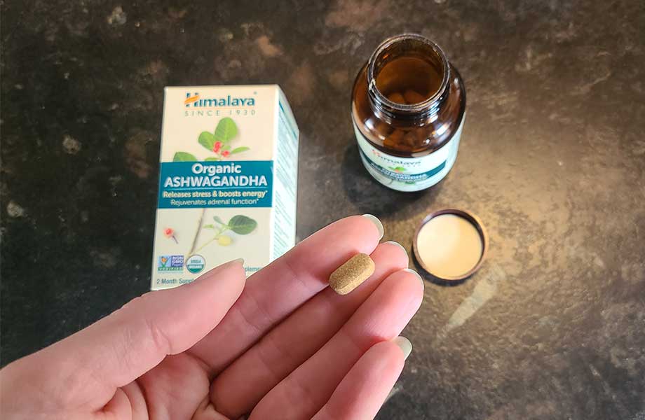 A hand holding a pill of Himalaya Ashwagandha