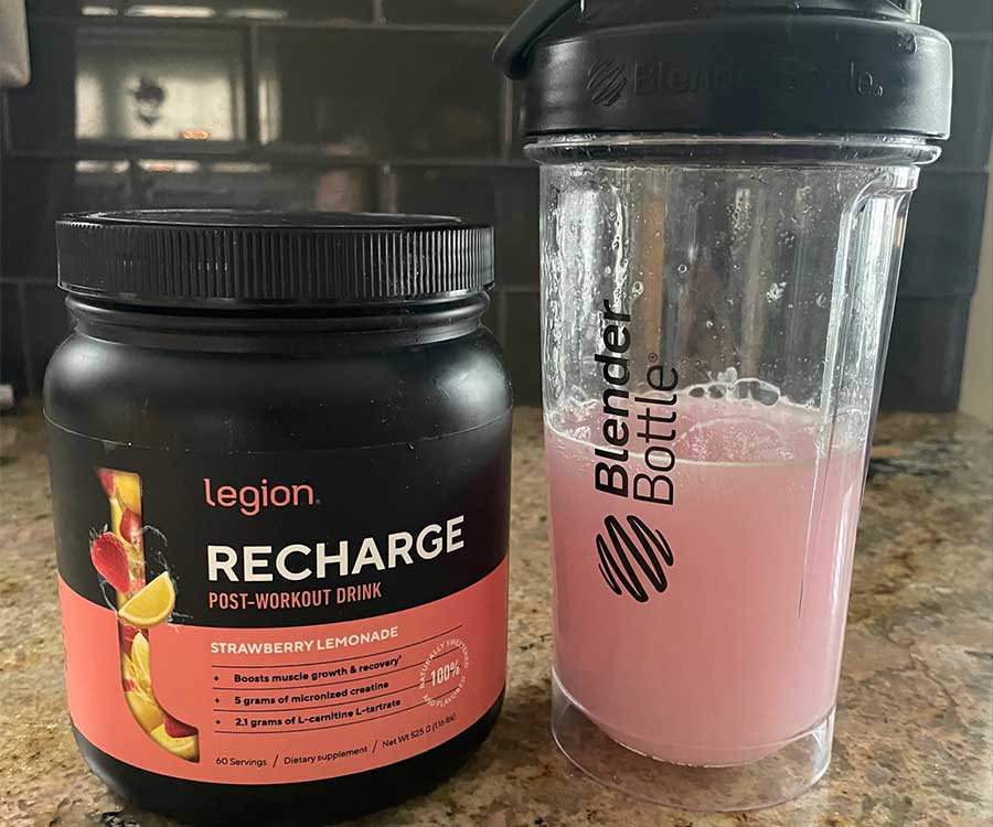 A container of Legion Recharge next to a shaker cup filled with the mixed post-workout  drink