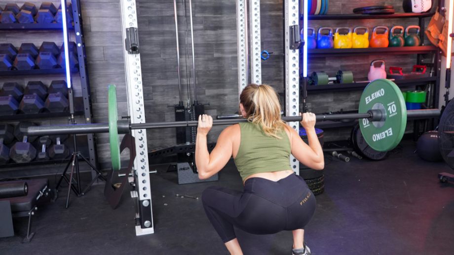 Woman squatting with the REP Fitness Helios Squat Bar