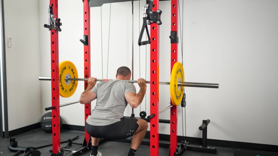 Man performing back squats in a red Major Lutie Power Rack