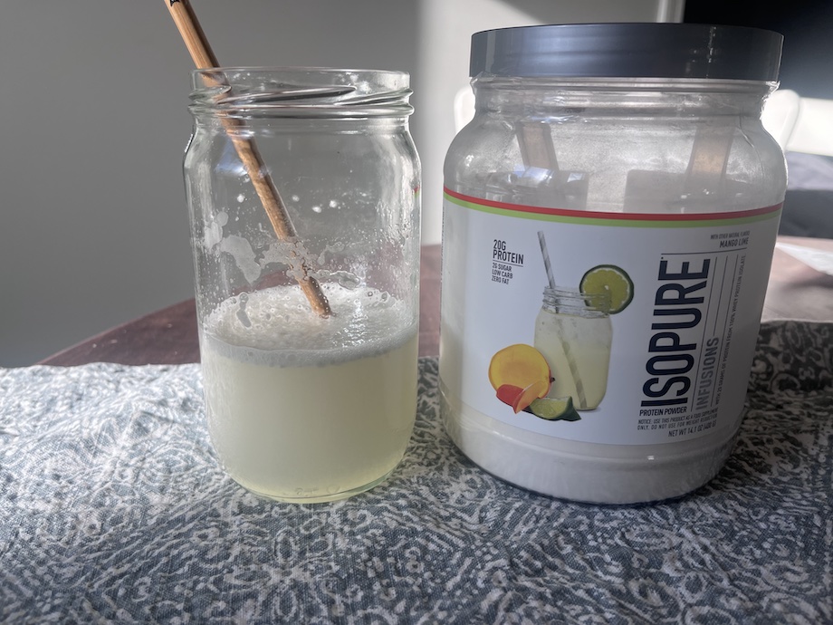 Isopure Clear Whey protein is shown mixed in a glass next to the container.