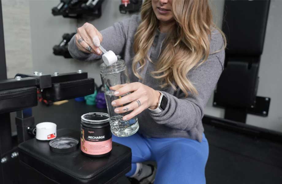 Woman pouring Legion Recharge into a water bottle