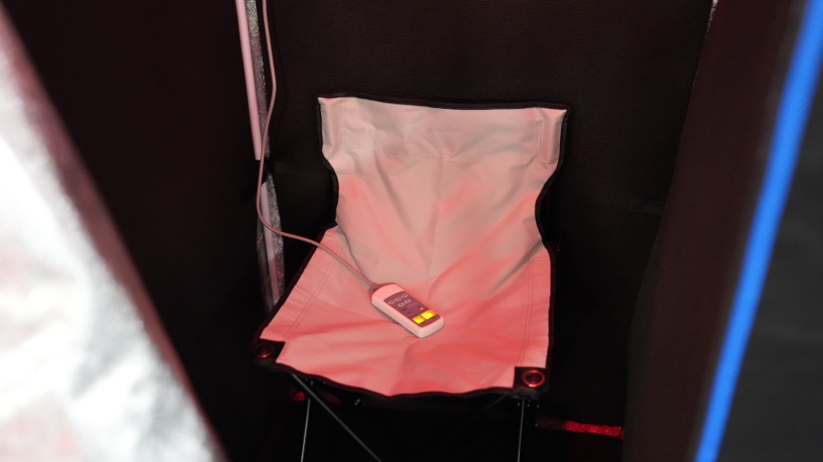Looking into the SereneLife Full Size Portable Infrared Sauna at the wired remote and what looks like a white canvas camping chair.