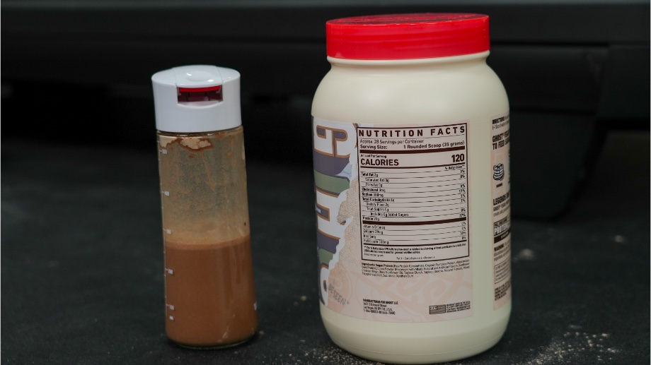 A shaker glass of Ghost Vegan Protein next to the Nutrition Facts label on the container.