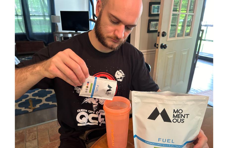 A man pouring a packet of Momentous Fuel into a shaker bottle with water