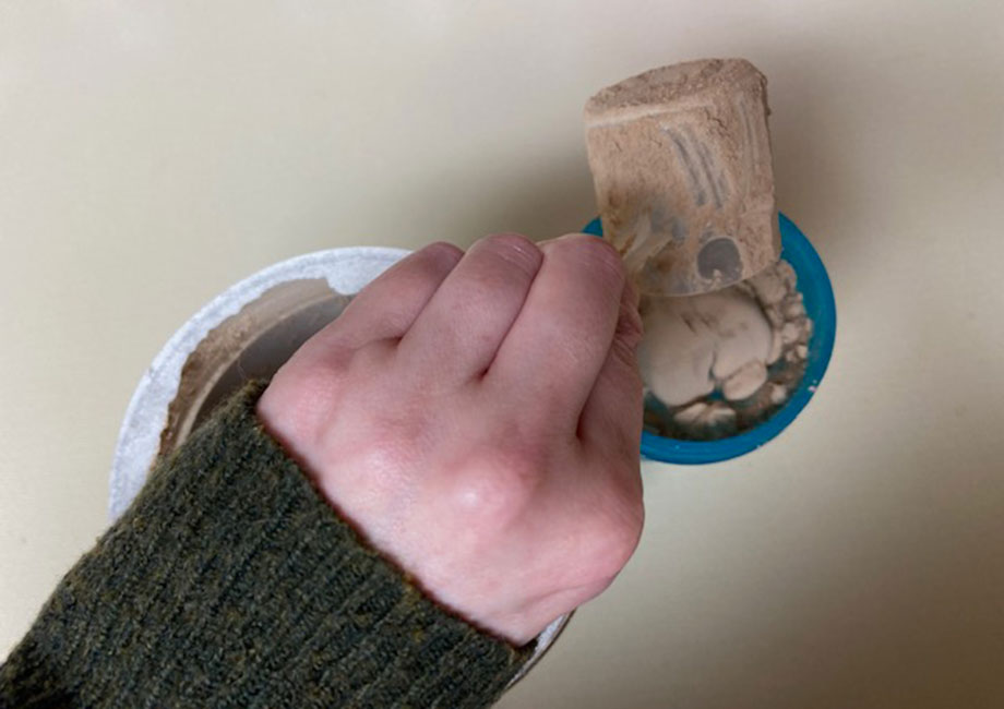 A scoop of Purely Inspired Organic Protein is being poured into a shaker cup.