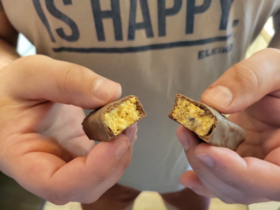 A person breaking a Think Protein Bar in half.