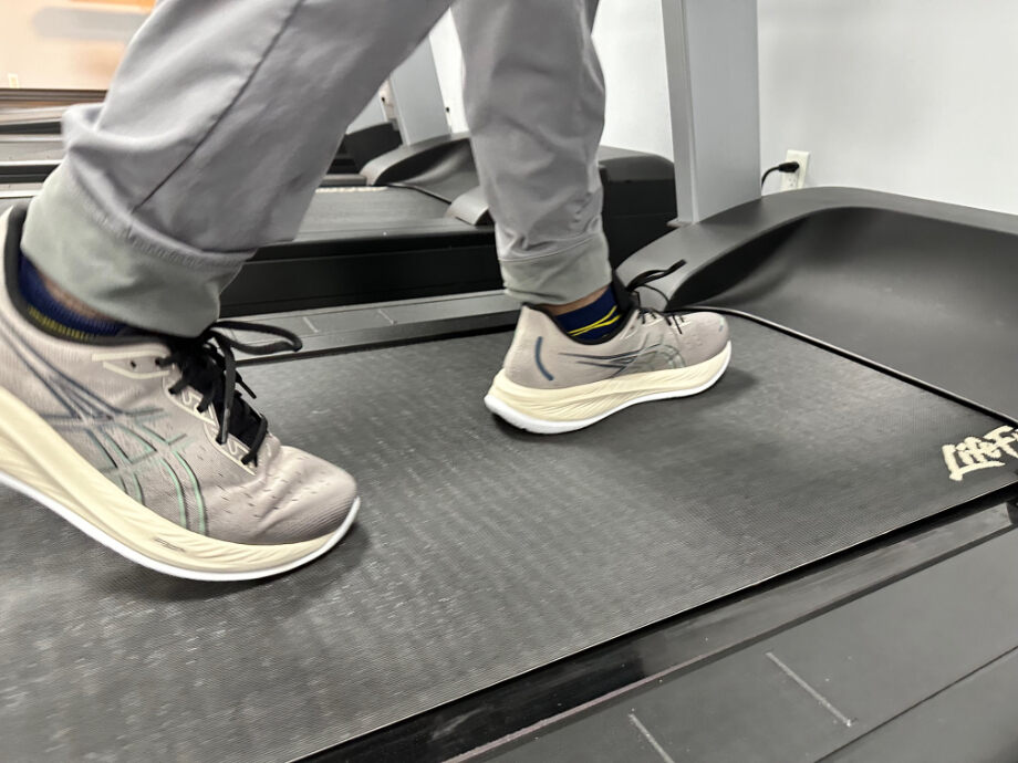 A close look at someone walking with Asics GEL-NIMBUS 26 recovery sneakers.