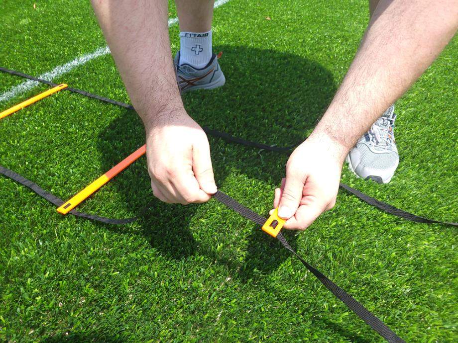 A person adjusts the GHB Pro Agility Ladder.