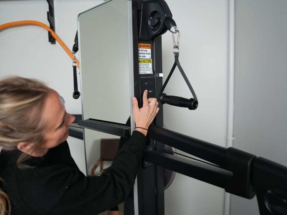 Pressing a button on the side of a NordicTrack Fusion CST machine.