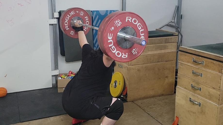 Olympian Caine Wilkes does an overhead squat with the Rogue Competition Bumpers.