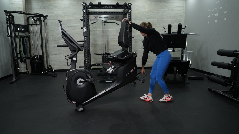 Full view of the Sole LCR Recumbent Bike while a person lifts it.