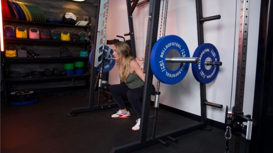 Side view of someone doing a squat with the Titan Smith Machine.