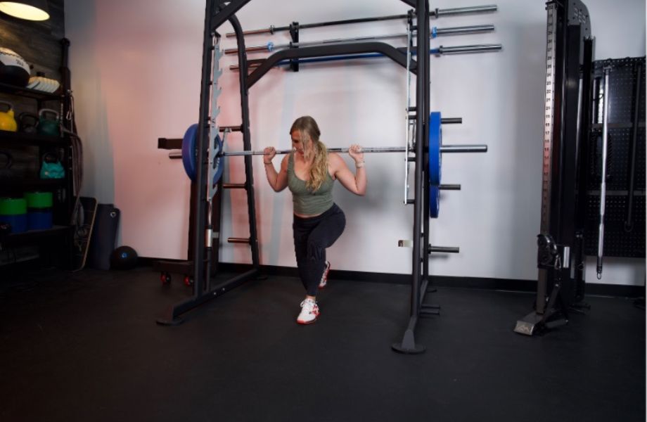 A woman does split squats with a Titan Smith Machine.