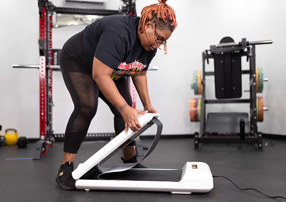 Woman in leggings and a t-shirt folding up the WalkingPad