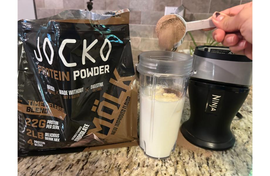 A person mixing Jocko protein powder in a blender