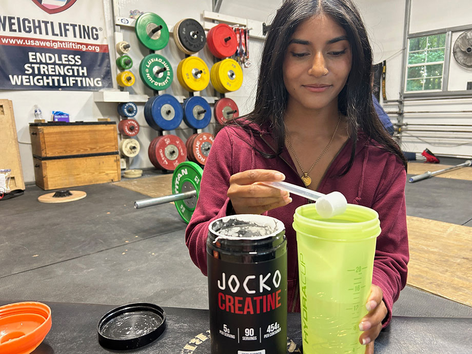 A person mixing Jocko Creatine into a shaker cup