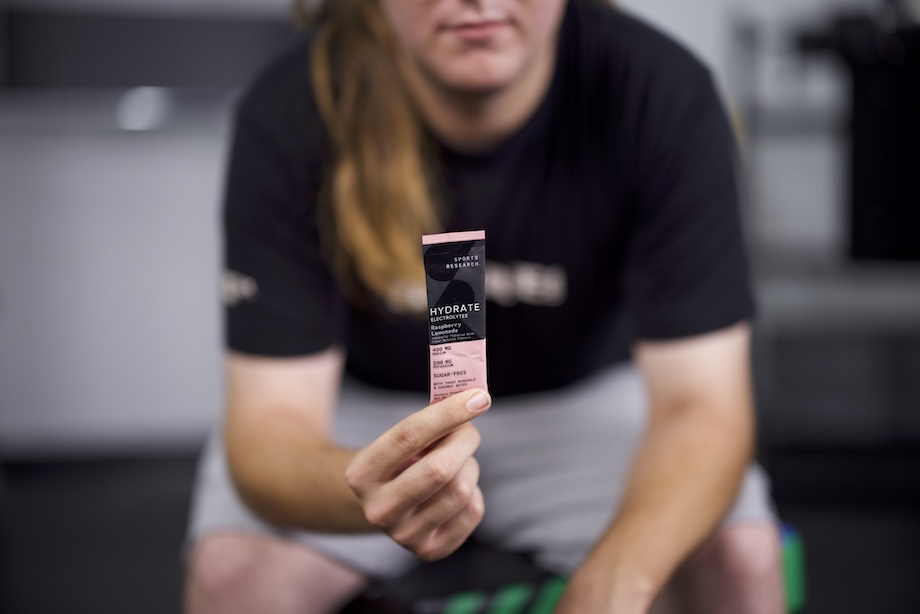 An image of a person holding a packet of Sports Research Hydrate electrolytes