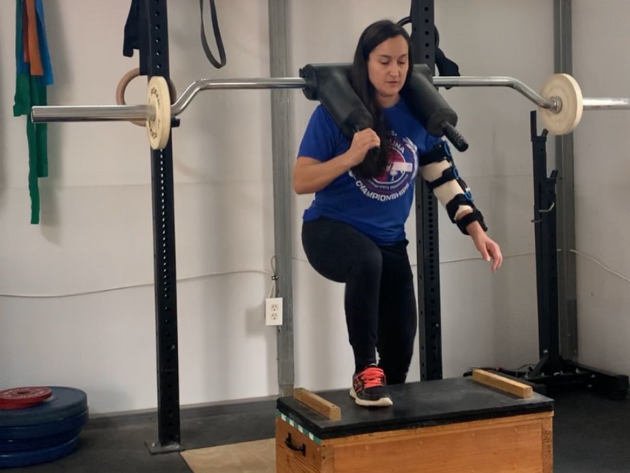 An injured woman uses the Titan Fitness Sqfety Squat Bar to perform step-ups