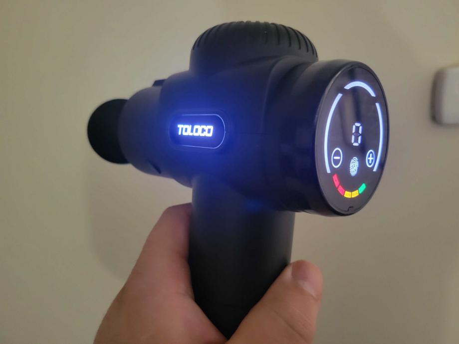 A man holds the TOLOCO Massage Gun while it's turned on