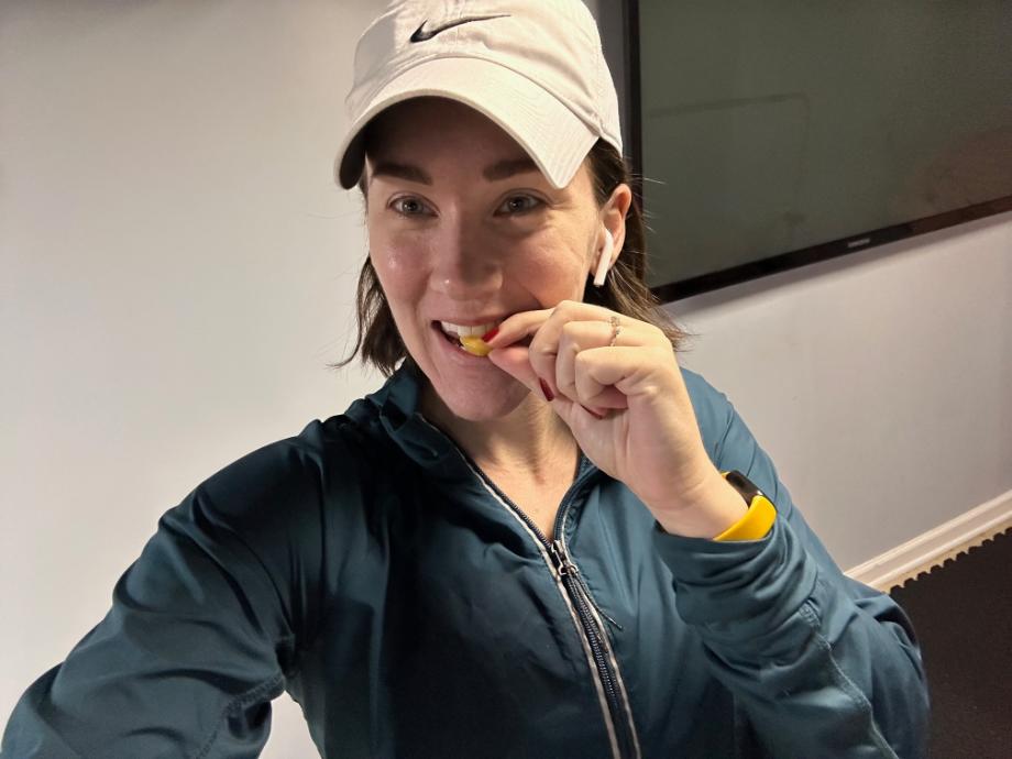 A woman takes a bite of a Legion creatine gummy in her home gym