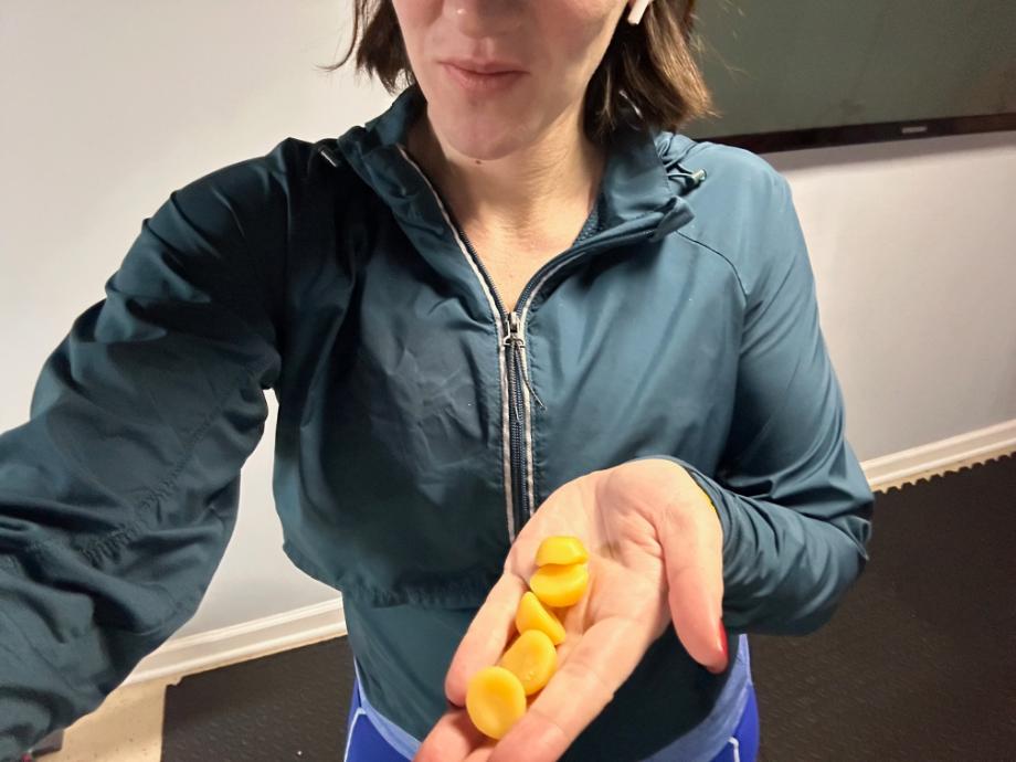 A woman holds a serving of five Legion creatine gummies in her hand