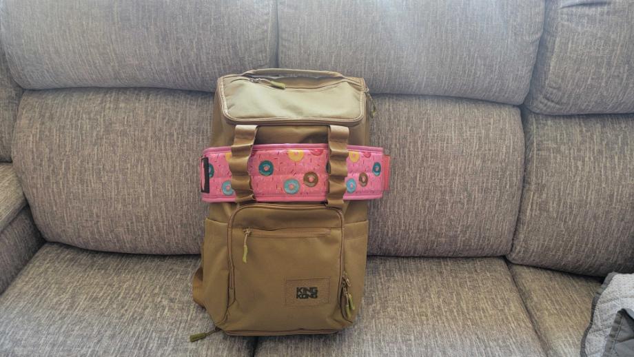 A KNKG CORE Gym Backpack rests on a couch with a belt