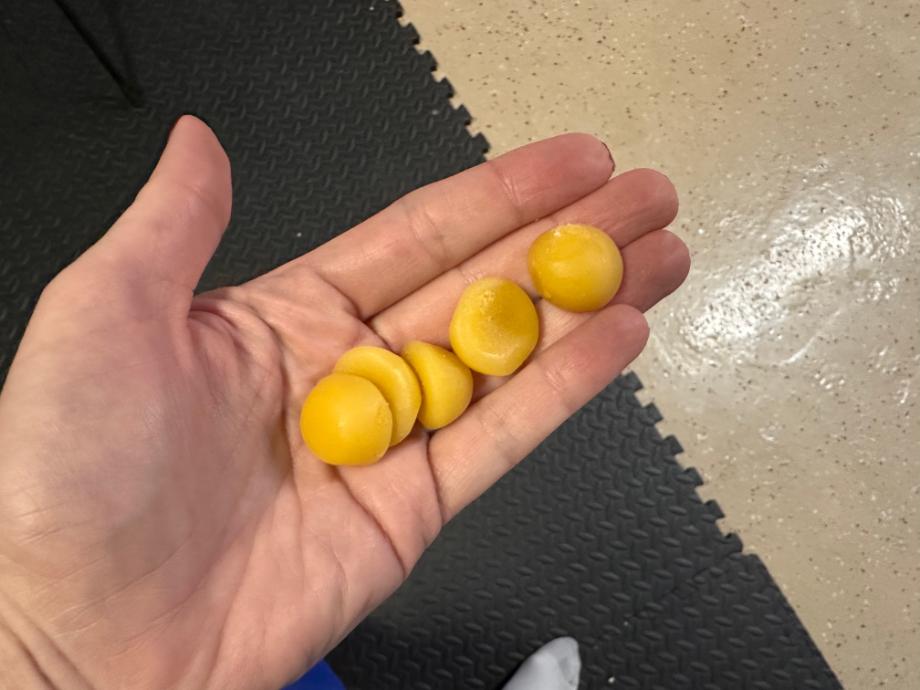 A hand holds out five Legion Creatine Gummies, the serving size