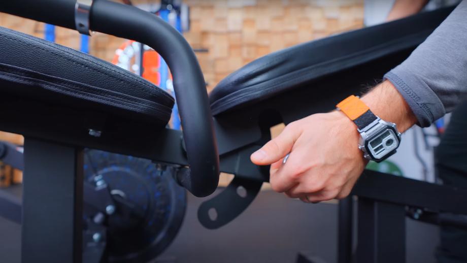 A close look as Coop adjusts the back pad for a RitFit PLC01 Leg Extension Curl Machine