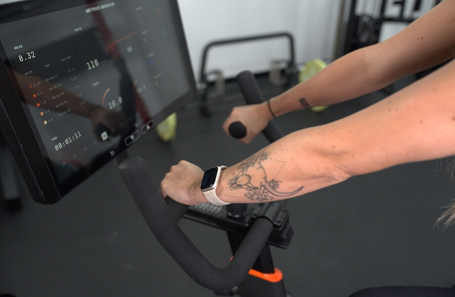 Our tester gripping the multi-grip handlebars while following along to a workout on the Aviron Fit Bike